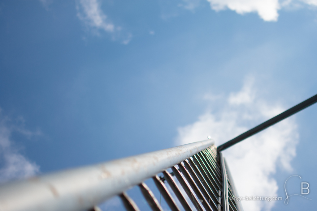 Foto von einer Leiter, die in den Himmel ragt. Der Himmel ist strahlend blau. Nur ein paar Wolkenfetzen sind zu sehen.