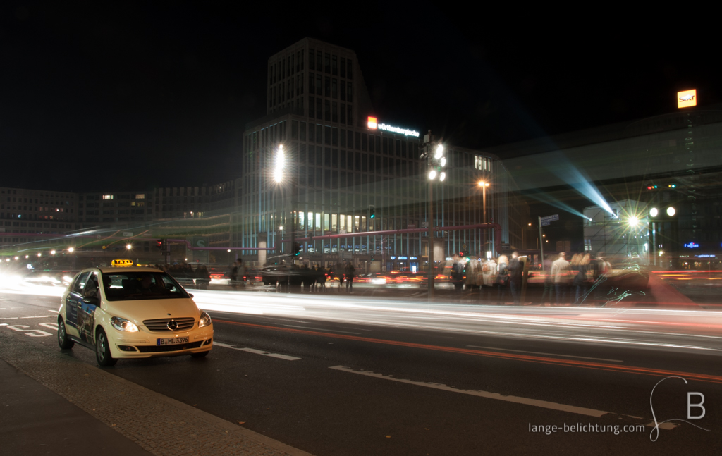 Ein Taxi steht am Potsdamer Platz und wartet auf Fahrgäste während drumherum das Leben pulsiert.